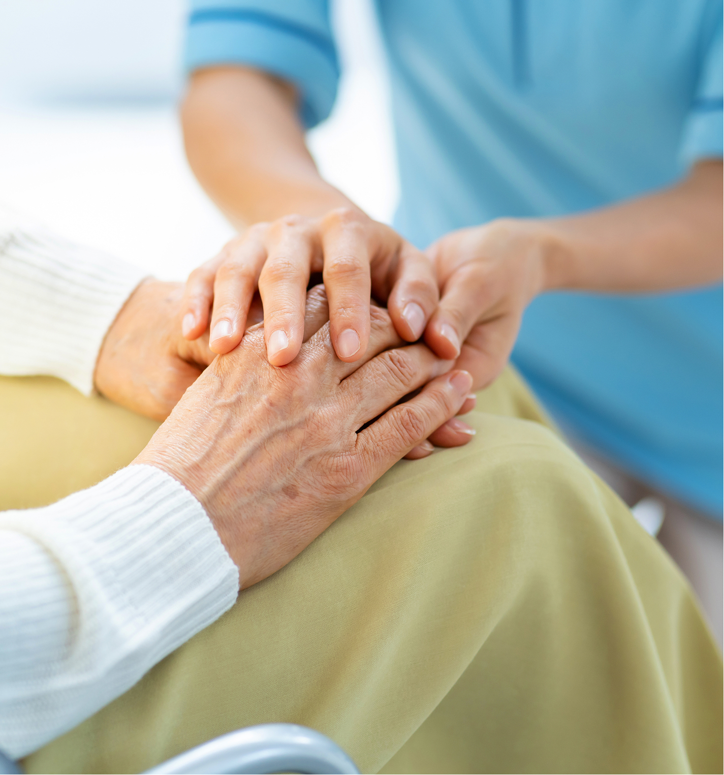 介護士が高齢者の手を優しく握っている様子