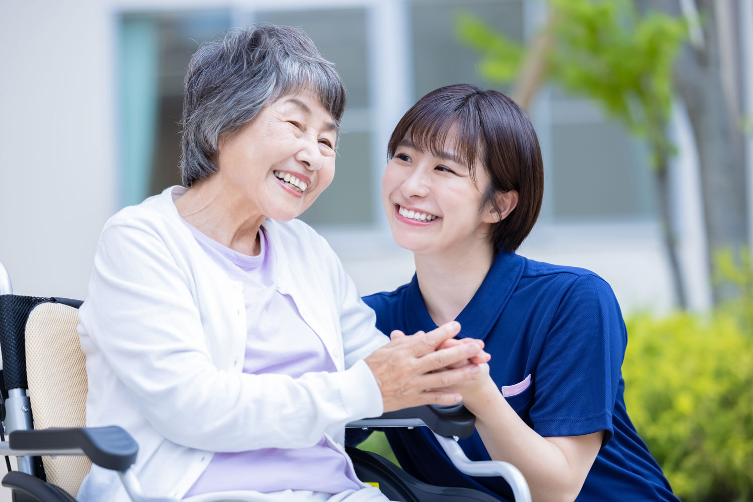 公園を歩く高齢者と介護士の後ろ姿